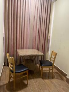 a table and two chairs in a room with a curtain at BLUE SKY GUEST HOUSE in Phnom Penh