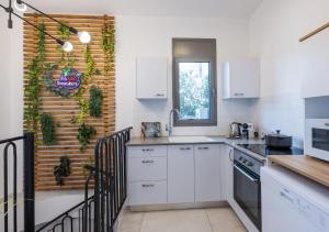 a kitchen with white cabinets and a wall with plants at Beach & Market Designed Duplex in Tel Aviv