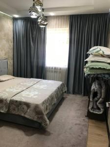 Schlafzimmer mit einem Bett und einem Fenster mit Vorhängen in der Unterkunft Sergeli 9 Resedens in Taschkent
