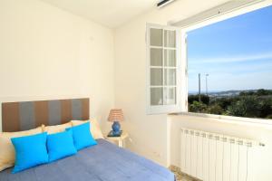 - une chambre avec une grande fenêtre et un lit avec des oreillers bleus dans l'établissement La Perla Bianca, à Gagliano del Capo