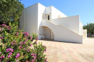 une maison blanche avec un escalier et des fleurs dans l'établissement La Perla Bianca, à Gagliano del Capo