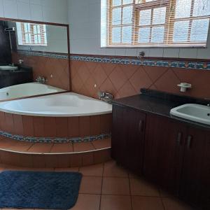 La salle de bains est pourvue d'une baignoire, d'un lavabo et d'un miroir. dans l'établissement Pandora's Guest Lodge, à Klerksdorp