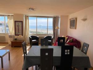 een woonkamer met een tafel en stoelen en uitzicht op de oceaan bij Appartement face à la mer in Cap d'Agde