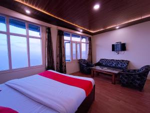 a bedroom with a bed and a couch and a tv at Surya Resort Dalhousie in Dalhousie