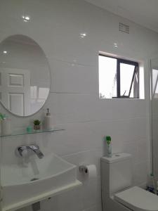 a white bathroom with a sink and a mirror at Inkazimulo Airbnb in Estcourt