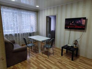sala de estar con mesa y TV en la pared en Квартира посуточно, en Shchūchīnsk