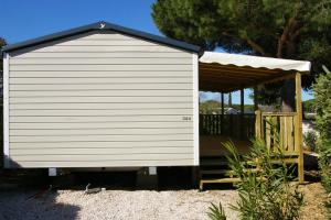 een grote witte schuur met een houten veranda bij Mobile Home OuiReves 344 facing the Mediterranean in Lattes