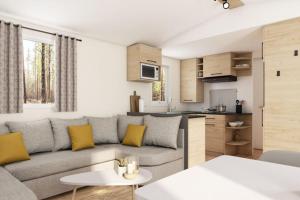 een woonkamer en een keuken met een grijze bank en gele kussens bij Mobile Home OuiReves 344 facing the Mediterranean in Lattes
