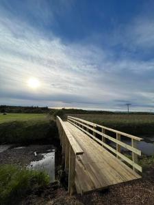 un puente de madera sobre un río con el sol en el cielo en Eiðar - Hostel, en Eiðar
