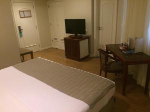 um quarto com uma cama, uma secretária e uma televisão em Olinda Rio Hotel no Rio de Janeiro