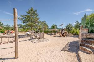einen Spielplatz mit Schaukeln und einem Zaun im Sand in der Unterkunft Ferienblockhaus 5 in Löwenstein