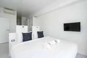 a white bedroom with a large white bed and a tv at Best View Apartment in Koh Samui 