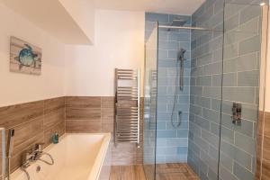 a bathroom with a tub and a shower with blue tiles at Ultimate Harbourside in Ilfracombe