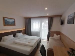 um quarto de hotel com duas camas e uma mesa em Gästehaus Holaus em Mayrhofen