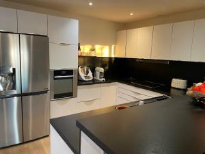 uma cozinha com armários brancos e um frigorífico de aço inoxidável em Domaine des Tuilières avec piscine em Vallauris