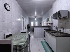 uma cozinha com uma mesa e um lavatório em Casa individual aconchegante - Rio da praia - Bertioga em Bertioga