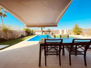 un patio con mesa, sillas y piscina en 3053 Malibu, en Orihuela