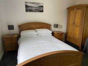 1 dormitorio con 1 cama grande de madera y 2 mesitas de noche en Blinkbonnie Guest House, en Portpatrick
