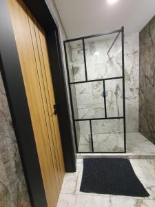 uma casa de banho com uma cabina de duche ao nível do chão ao lado de uma porta em City apartment 2 bedrooms em Siauliai