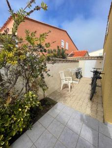 un vélo garé à côté d'un mur avec une table et des chaises dans l'établissement Charmante Villa de vacances, au Cap d'Agde