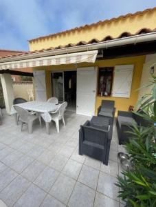 a patio with a table and chairs and a house at Charmante Villa de vacances in Cap d'Agde