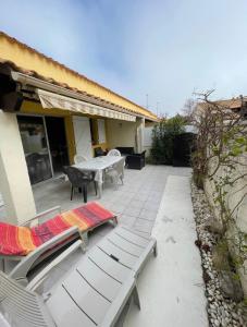 un patio con 2 sillas, una mesa y un banco en Charmante Villa de vacances en Cap d'Agde