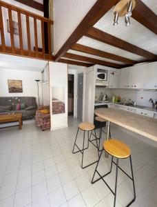 a kitchen and living room with a table and stools at Charmante Villa de vacances in Cap d'Agde