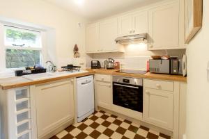 a kitchen with white cabinets and a checkered floor at Ivy Cottage in Skipton