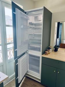 an empty refrigerator with its door open in a kitchen at Studio Remigny, hyper centre ville de Nevers, style "Appart-hôtel" by PRIMO C0NCIERGERIE in Nevers