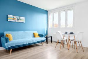 ein Wohnzimmer mit einem blauen Sofa und einem Tisch in der Unterkunft Appartement Prestige - Amiens in Amiens