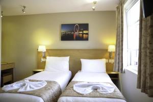 two beds in a hotel room with towels at Kings Cross Inn Hotel in London