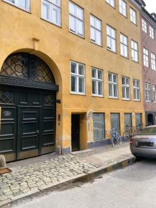 a yellow building with black doors on a street at ApartmentInCopenhagen Apartment 980 in Copenhagen