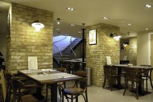 a restaurant with tables and chairs and a brick wall at Kings Cross Inn Hotel in London