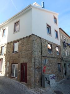 ein Steingebäude mit einer roten Tür auf einer Straße in der Unterkunft Ritta´s House - Covilhã in Covilhã