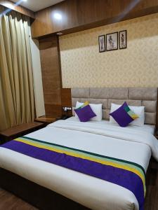 a bedroom with a large bed with purple pillows at Nearmi Hotels Banquets Medanta IKEA Sector 47 - Gurugram in Gurgaon
