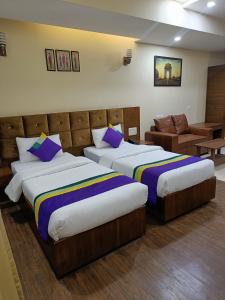 Habitación de hotel con 2 camas y sofá en Nearmi Hotels Banquets Medanta IKEA Sector 47 - Gurugram en Gurgaon