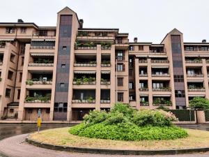 un gran edificio de apartamentos con un jardín delante de él en Parcheggio Privato - Appartamento a Milano, en Corsico