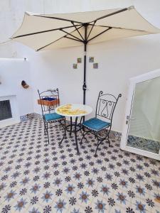 a table and chairs with an umbrella on a tiled floor at Ca'Turino in Vietri sul Mare