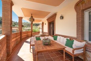 - une terrasse couverte avec un canapé et une table dans l'établissement Casa Rural Villa la Gaviota con Piscina y Barbacoa junto a Ruta del Gollizno en Olivares, à Olivares
