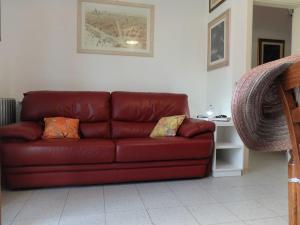 a red leather couch in a living room at Appartamento con giardino a 5 minuti dal mare in Torre del Lago Puccini