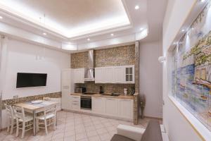 una cucina con armadi bianchi, tavolo e TV di Casa La Bifora a Sorrento