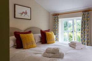 um quarto com uma cama branca com almofadas amarelas e vermelhas em 9 Gargrave Road at Broughton Sanctuary em Broughton