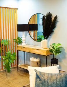 Mdumela Stays 2 Bedroom Modern City Apartment في بيترماريتزبورغ: مرآة على طاولة في غرفة مع نباتات