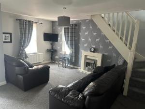 a living room with a couch and a stair case at 3 Dialknowe Holiday Cottage - Wanlockhead in Wanlockhead