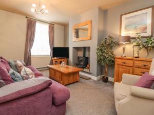 a living room with a purple couch and a tv at 21 West View in Clitheroe