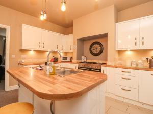 uma cozinha com armários brancos e um balcão de madeira em 21 West View em Clitheroe