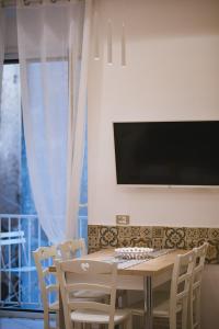 una sala da pranzo con tavolo, sedie e TV di Casa La Bifora a Sorrento