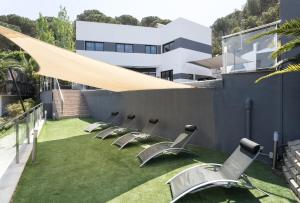 a row of chairs sitting on a lawn in front of a building at 5 bedrooms villa with private pool enclosed garden and wifi at Lloret de Mar 1 km away from the beach in Lloret de Mar