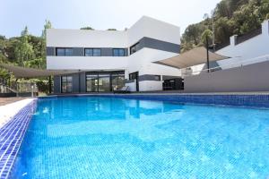 a swimming pool in front of a house at 5 bedrooms villa with private pool enclosed garden and wifi at Lloret de Mar 1 km away from the beach in Lloret de Mar