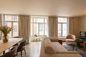 Dukes' Apartments Grand Place في بروج: غرفة معيشة مع أريكة وكراسي ونوافذ